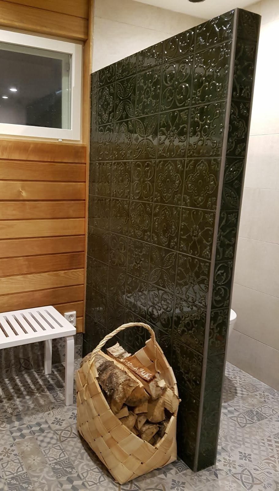 Näyttävä tehosteseinä tummanvihreillä koristekaakeleilla.